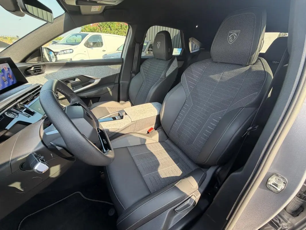 Vue intérieure côté conducteur du Peugeot 3008 Hybrid gris 2025, sièges GT avec logo Peugeot sur appuie-tête.
