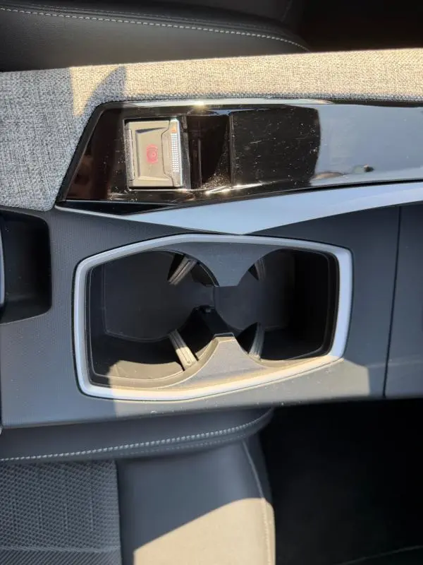 Gros plan sur la console centrale grise du Peugeot 3008 Hybrid 145 e-DCS6 GT avec porte-gobelets et frein à main électrique.