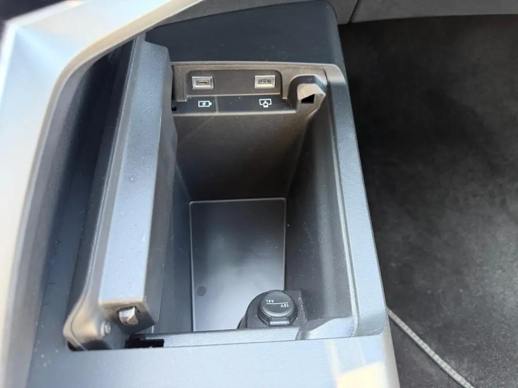 Gros plan sur le rangement intérieur avec prises USB et prise 12V du Peugeot 3008 Hybrid gris, version 2025.