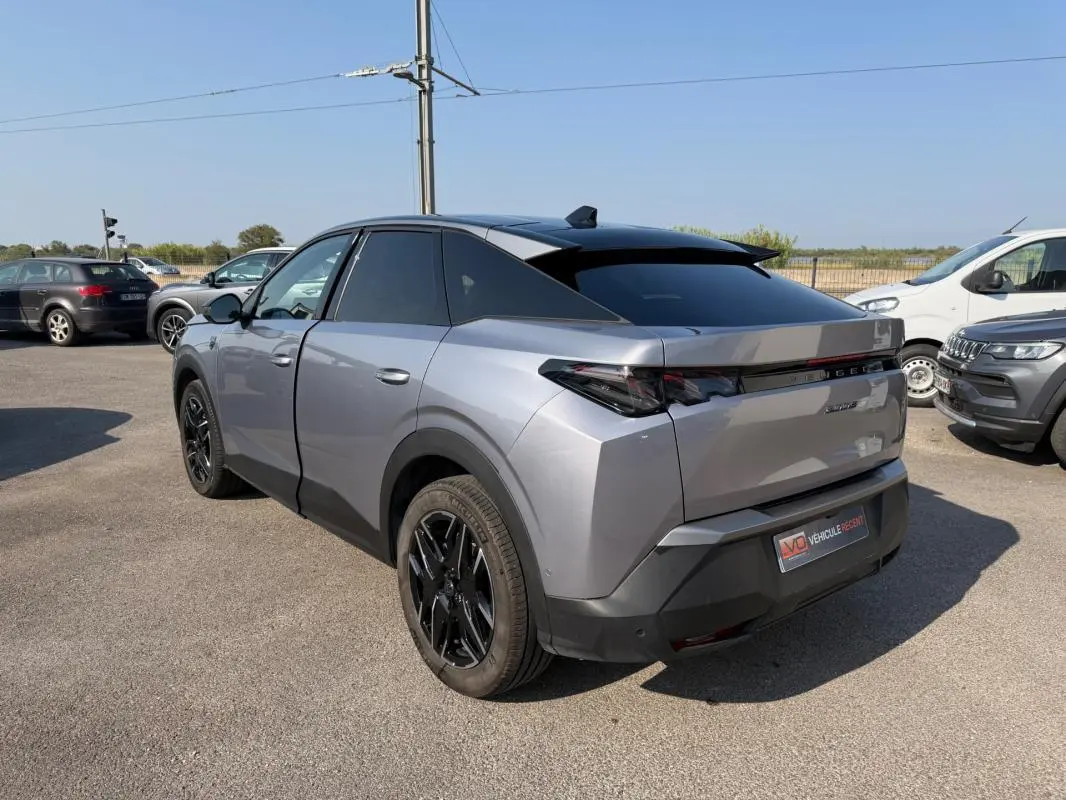 Vue 3/4 arrière droite d’un Peugeot 3008 Hybrid 145 gris avec jantes alliage noires de 19 pouces, sur parking extérieur.