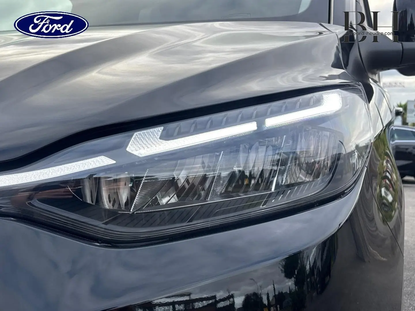 Gros plan sur le phare avant droit du Ford Transit Custom noir Agate Métallisée avec éclairage LED distinctif.