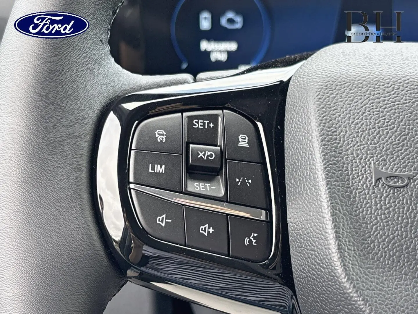 Gros plan sur les commandes multifonctions noires à gauche du volant gris du Ford Transit Custom Fourgon 2026.