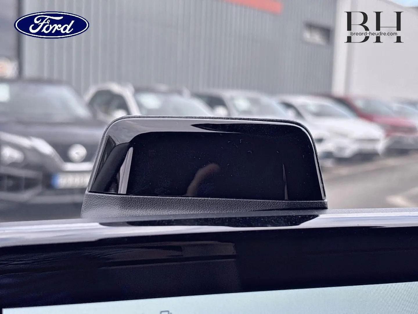 Gros plan sur l'antenne noire du Ford Transit Custom Fourgon 2026, couleur Noir Agate Métallisée, en extérieur flou.