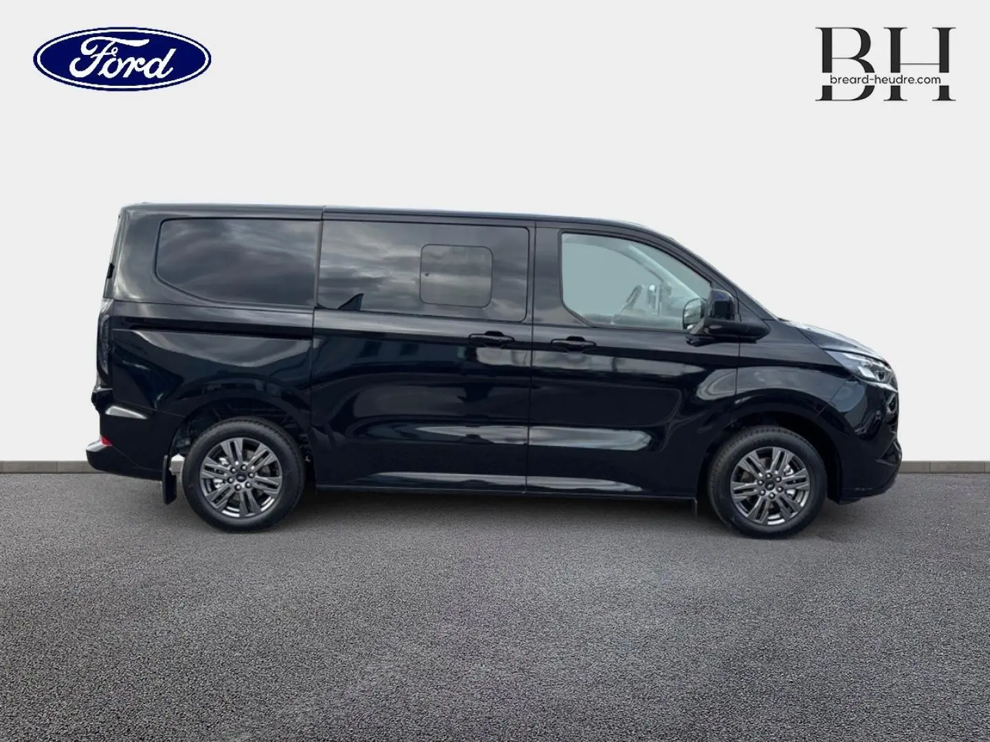 Vue latérale droite d'un Ford Transit Custom Fourgon noir Agate Métallisée avec jantes alu gris carbone et porte latérale coulissante double.