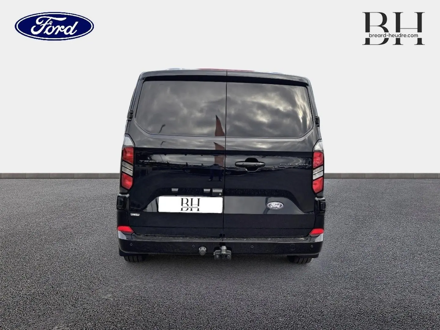 Vue arrière d'un Ford Transit Custom Fourgon noir Agate Métallisée avec crochet d'attelage et vitres arrière surteintées.