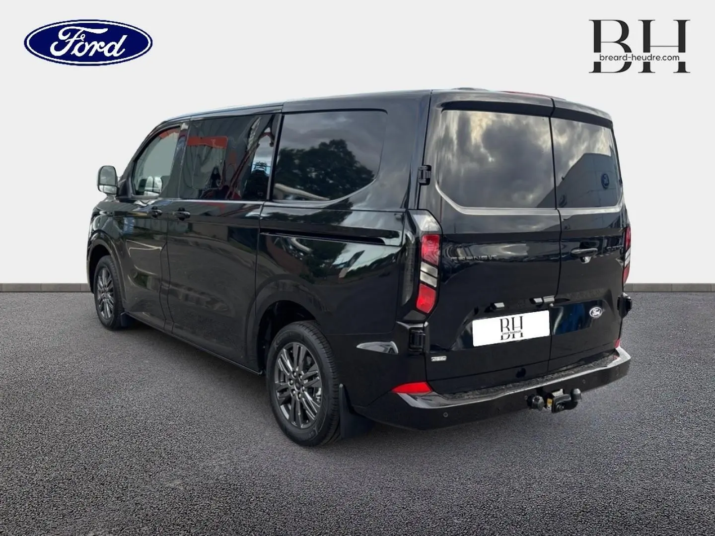 Vue 3/4 arrière droite du Ford Transit Custom Fourgon noir Agate Métallisée avec crochet d'attelage et jantes alu gris carbone.