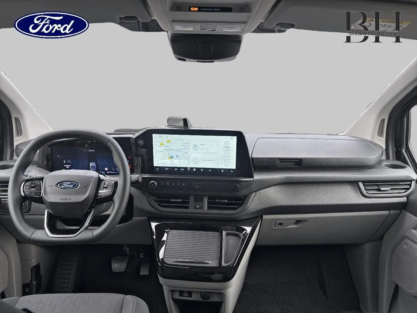 Vue intérieure avant du Ford Transit Custom Fourgon 2026, tableau de bord moderne avec écran tactile central et volant multifonction noir.