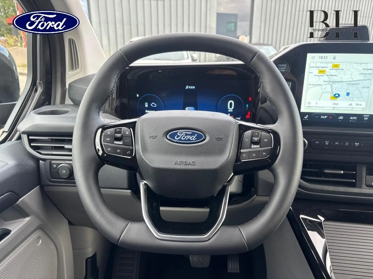 Vue frontale du volant et tableau de bord numérique du Ford Transit Custom Fourgon noir, avec écran tactile de navigation.