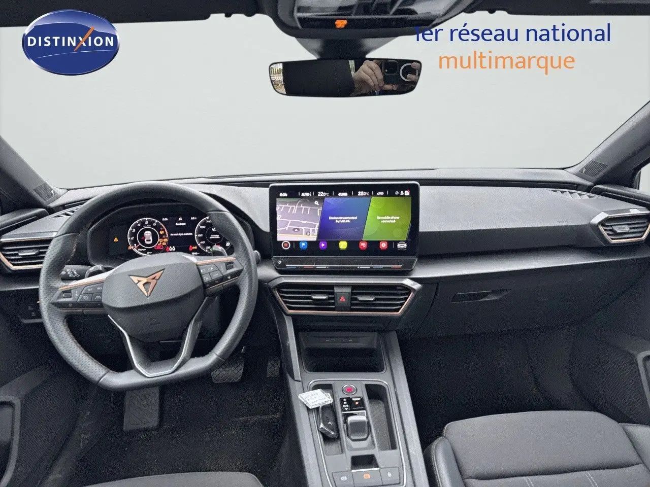 Vue intérieure frontale du tableau de bord et volant noir de la CUPRA LEON ST 2024 avec écran tactile central allumé.