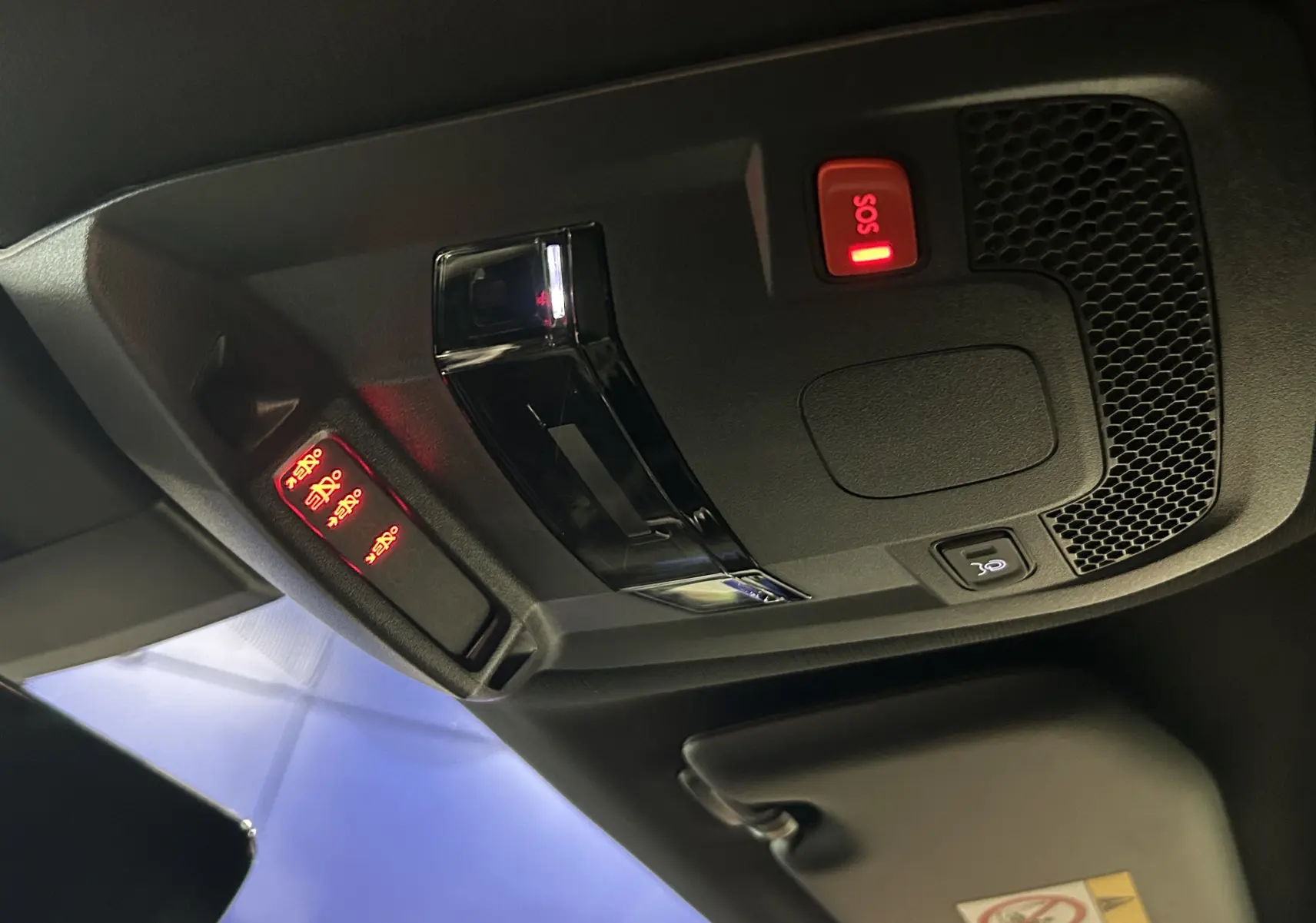 Vue intérieure du plafond de la Peugeot 508 SW 2024, montrant les commandes d'urgence SOS et l'éclairage ambiant rouge.