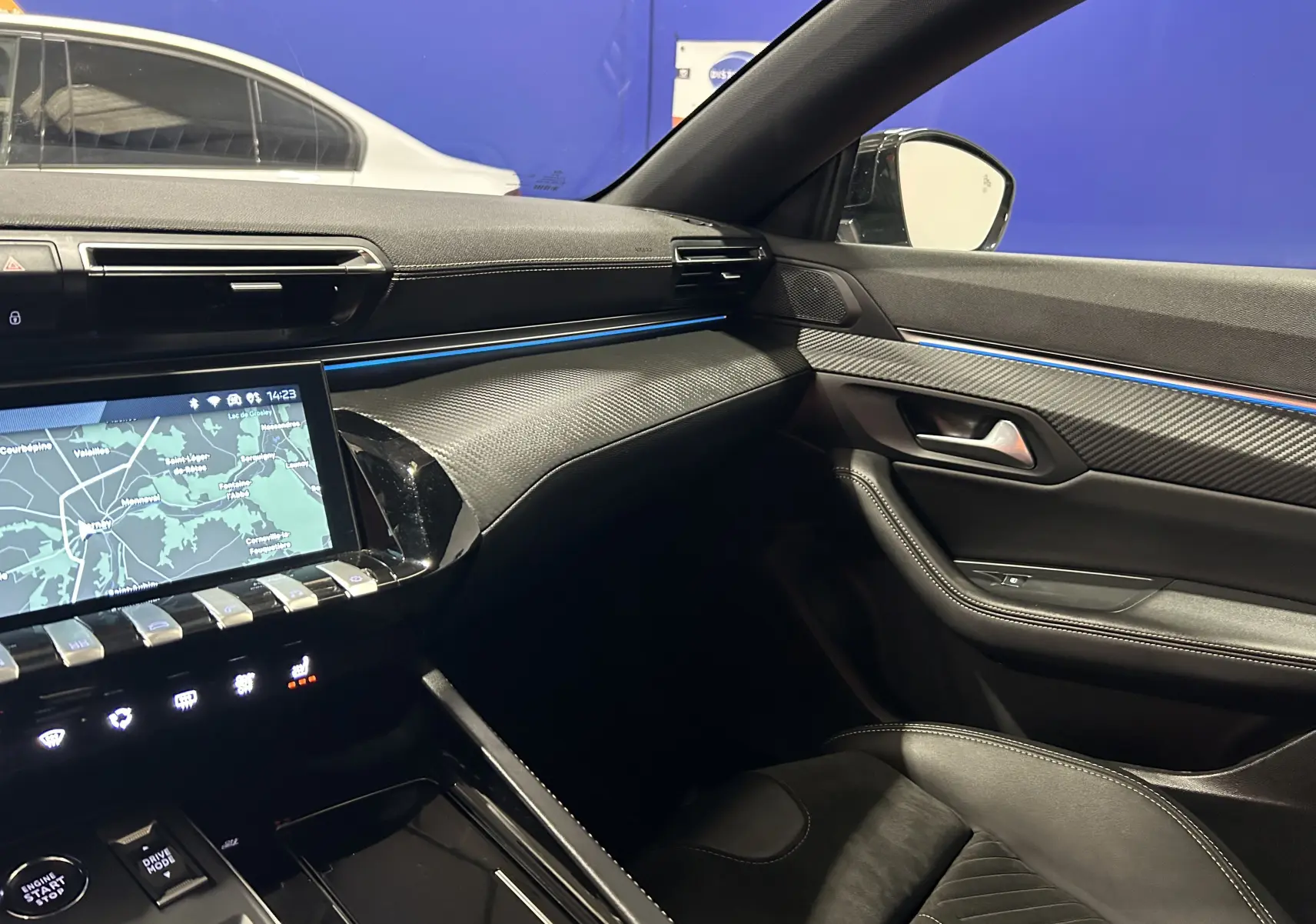 Intérieur côté passager du Peugeot 508 SW 2024 gris Selenium, avec tableau de bord noir et éclairage d'ambiance bleu fin.