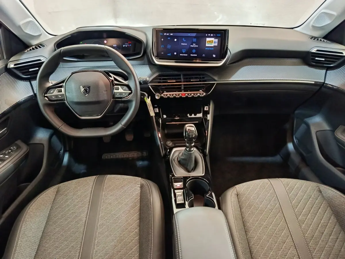 Intérieur Peugeot 208 PureTech 100 S&S Allure 2025, vue avant centrée sur tableau de bord et volant cuir multifonctions.