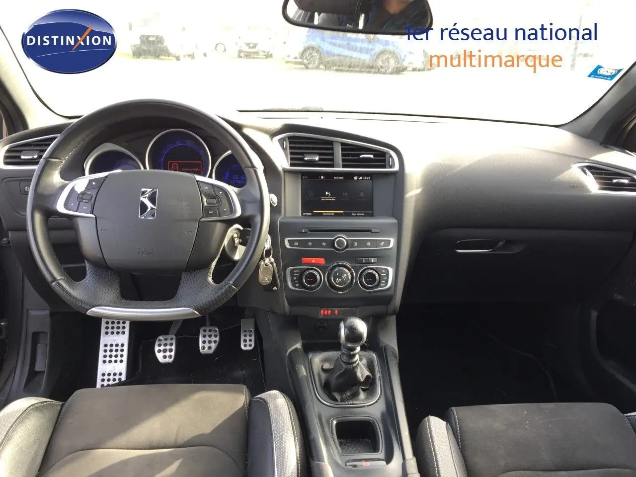 Vue intérieure avant du DS4 CROSSBACK gris platinium, mettant en valeur le volant multifonction et la boîte manuelle.