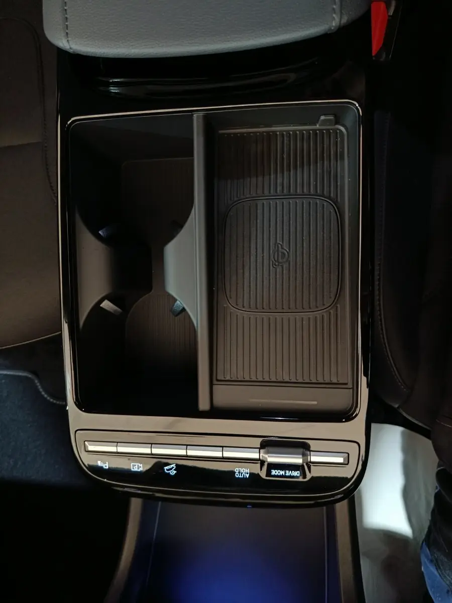 Vue plongeante sur la console centrale noire du Hyundai Tucson 1.6 Hybrid 2025 avec zone de recharge sans fil et commandes tactiles.