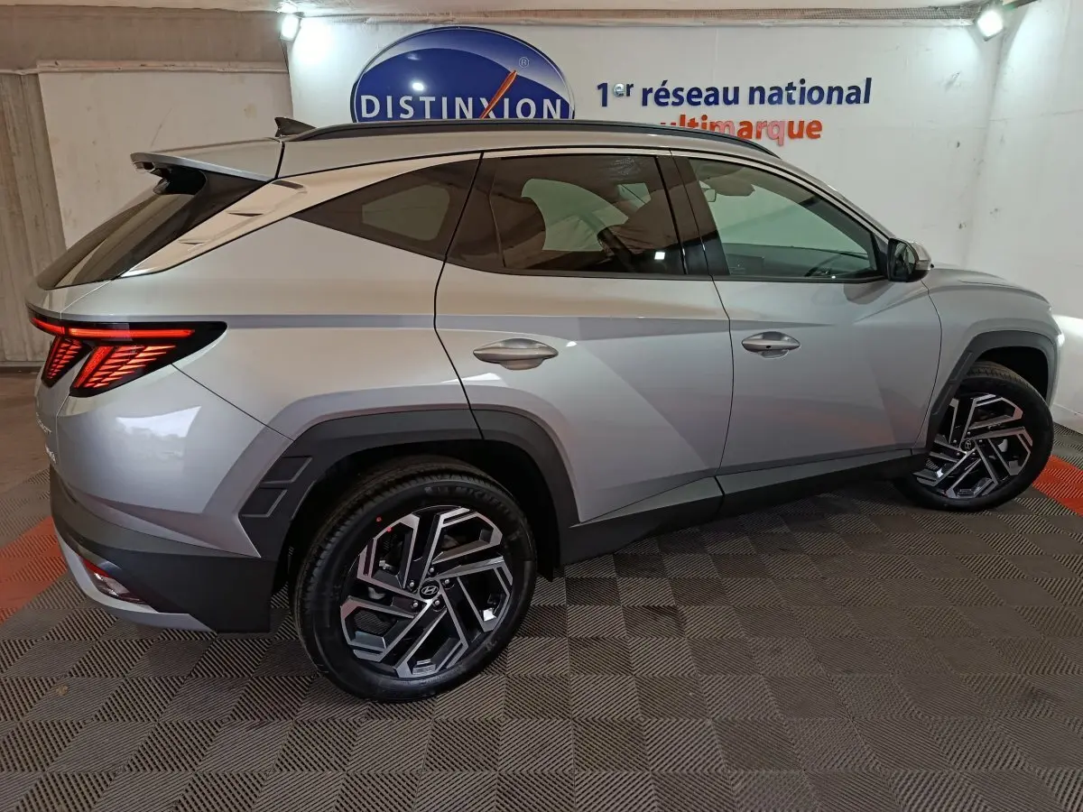 Vue latérale droite d'un Hyundai Tucson 1.6 Hybrid gris clair avec feux arrière LED et jantes alliage distinctives.