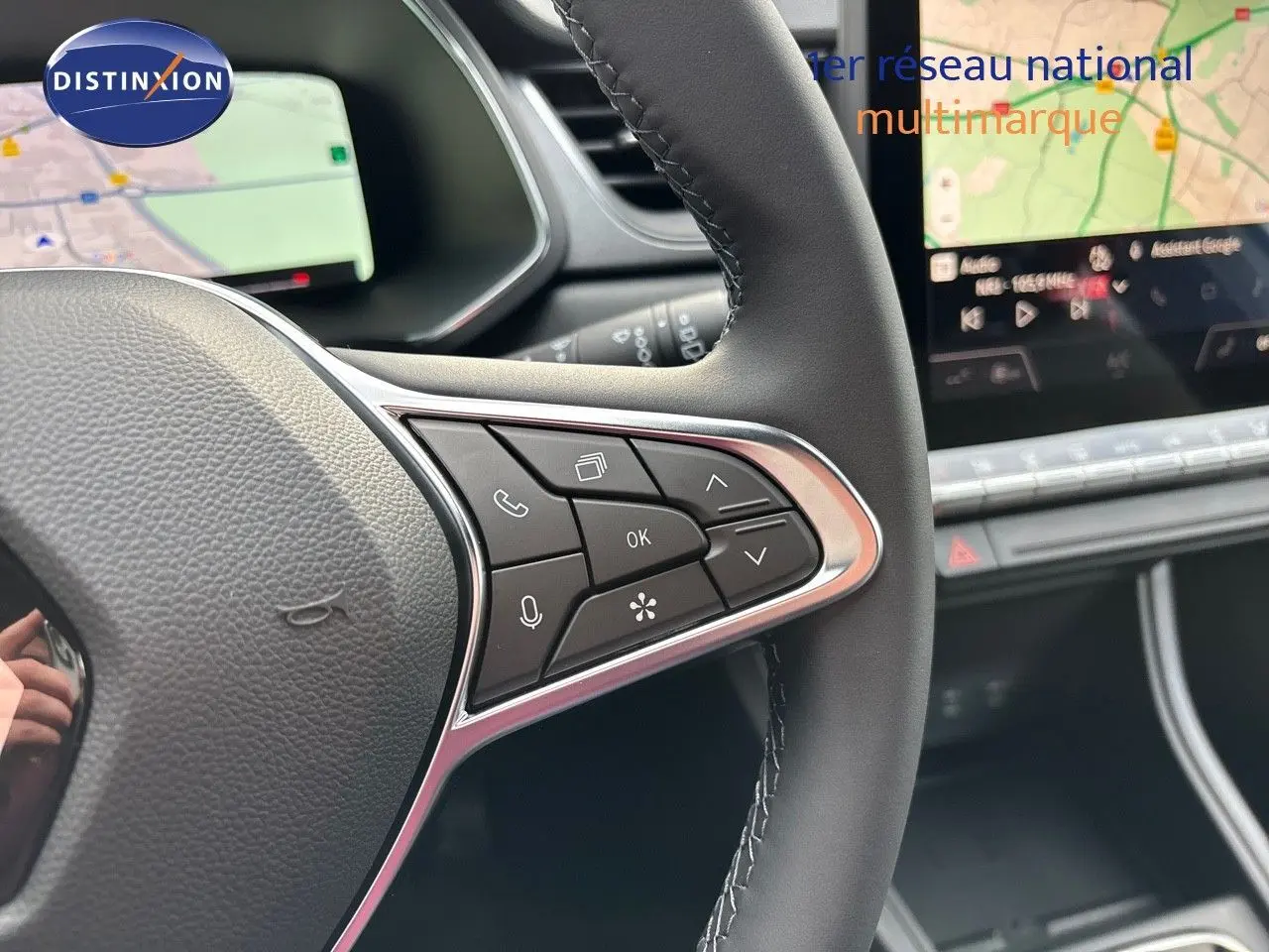Gros plan sur le volant cuir noir du Renault Captur 2025, avec commandes multifonctions et écran tactile de navigation en arrière-plan.