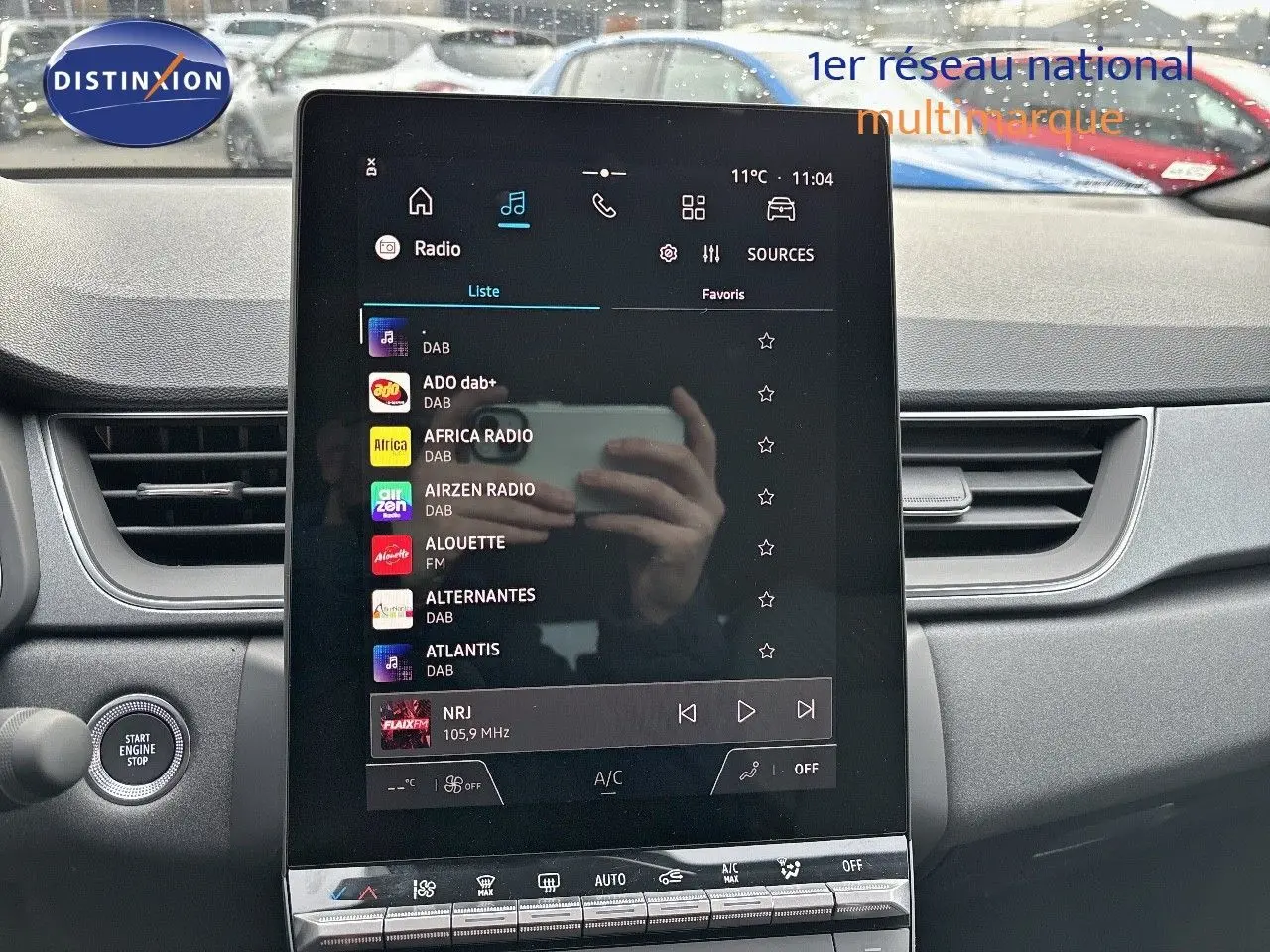 Vue rapprochée de l’écran tactile central du Renault Captur II hybride 2025, affichant les stations radio, avec tableau de bord gris.
