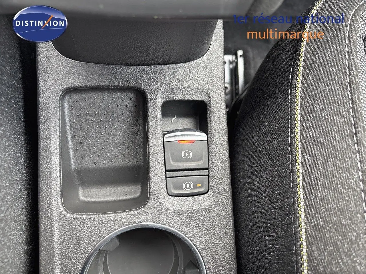 Vue rapprochée de la console centrale du Renault Captur gris rafale métal, avec commandes de frein à main électronique et tissu noir.