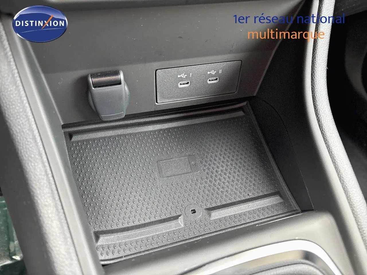 Gros plan sur la console centrale du Renault Captur II hybride 2025, montrant les ports USB-C et un espace de rangement noir texturé.