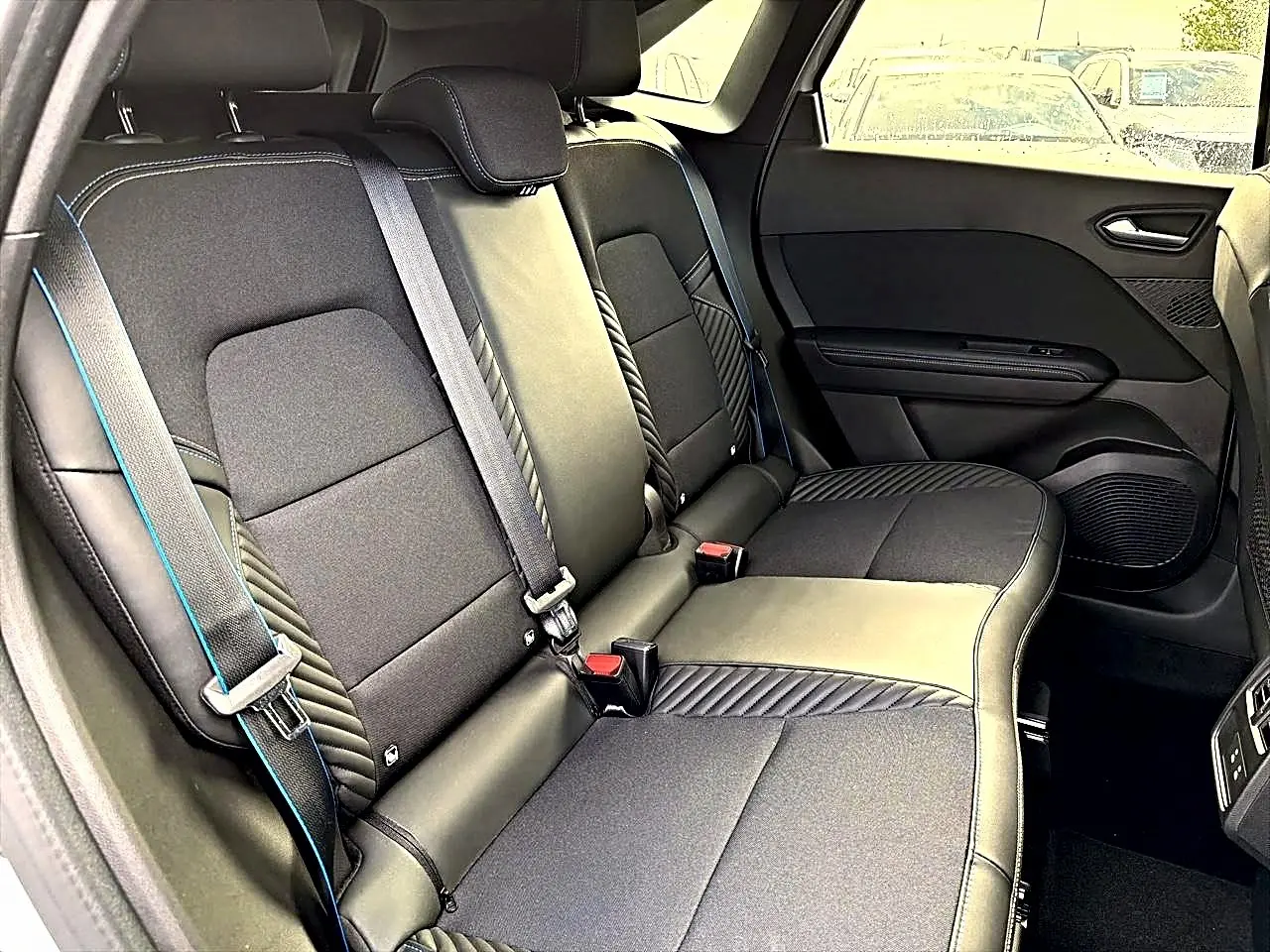 Vue intérieure de la banquette arrière noire avec surpiqûres bleues du Renault Symbioz gris rafale, version hybride 2026.