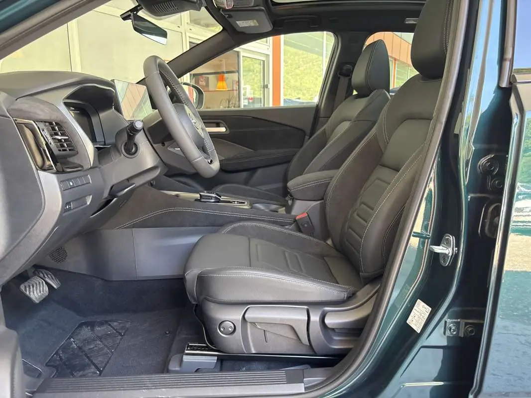 Vue côté gauche de l’intérieur du Nissan Qashqai E-POWER 205 N-DESIGN vert cayuga, sièges cuir alcantara noirs et tableau de bord moderne.