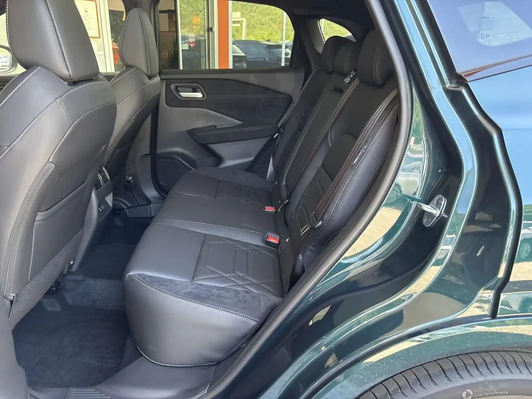 Vue côté droit de la banquette arrière en cuir alcantara noir du Nissan Qashqai E-POWER 2026 vert cayuga avec porte ouverte.