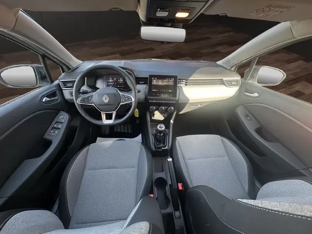 Vue intérieure avant de la Renault Clio V 2025, sellerie textile gris, volant multifonction, écran tactile central et boîte manuelle.