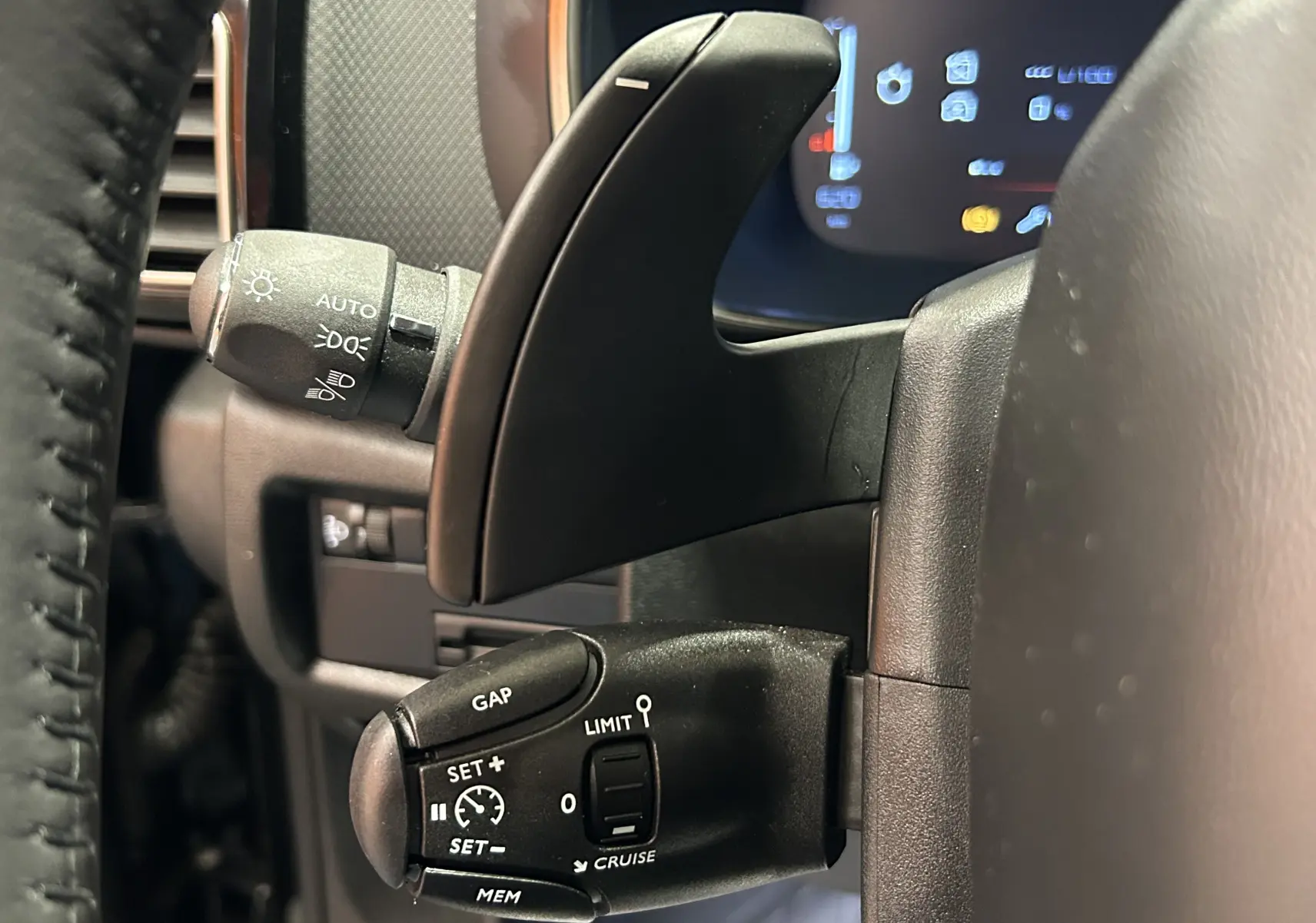 Détail du commodo noir à gauche du volant d'une Citroën C5 Aircross 2024, avec régulateur adaptatif visible.