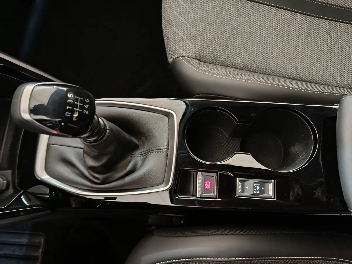 Vue rapprochée de la console centrale noire avec levier de vitesses manuel et porte-gobelets du Peugeot 208 gris clair