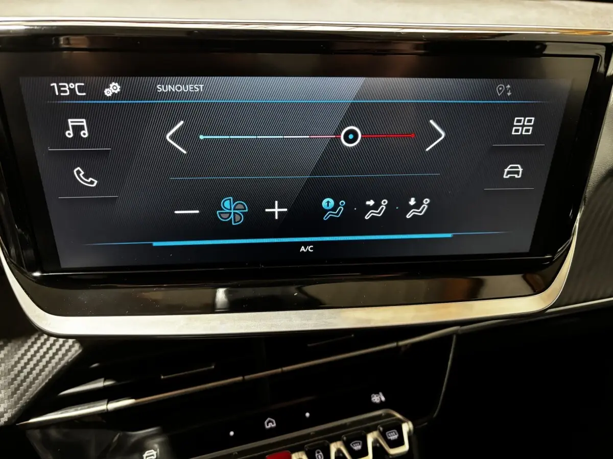 Écran tactile central affichant la climatisation dans l’habitacle noir du Peugeot 208 Hybrid 110 jaune, vue rapprochée.