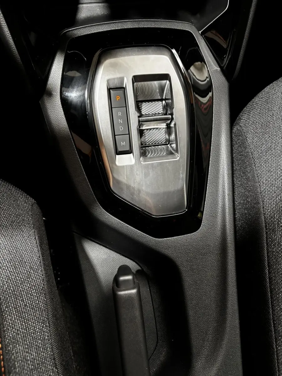 Gros plan sur la console centrale de la Peugeot 208 Hybrid 110, avec la commande de boîte automatique et frein à main manuel.