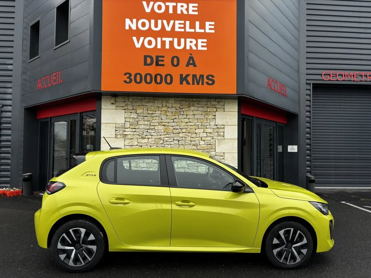 Vue de profil côté gauche d'une Peugeot 208 jaune hybride 2025 garée devant un bâtiment avec panneau orange.