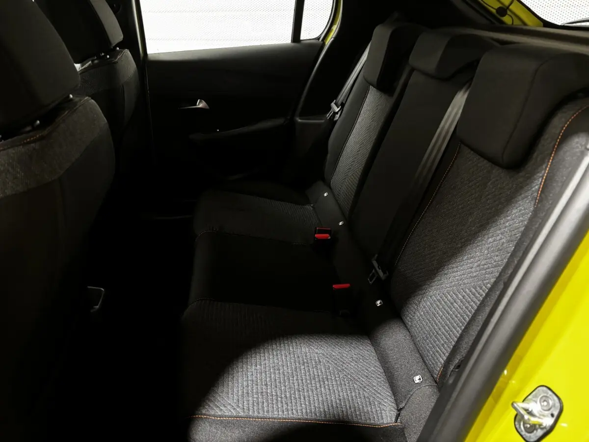 Vue intérieure côté droit des sièges arrière gris et noirs d'une Peugeot 208 jaune 2025 hybride.