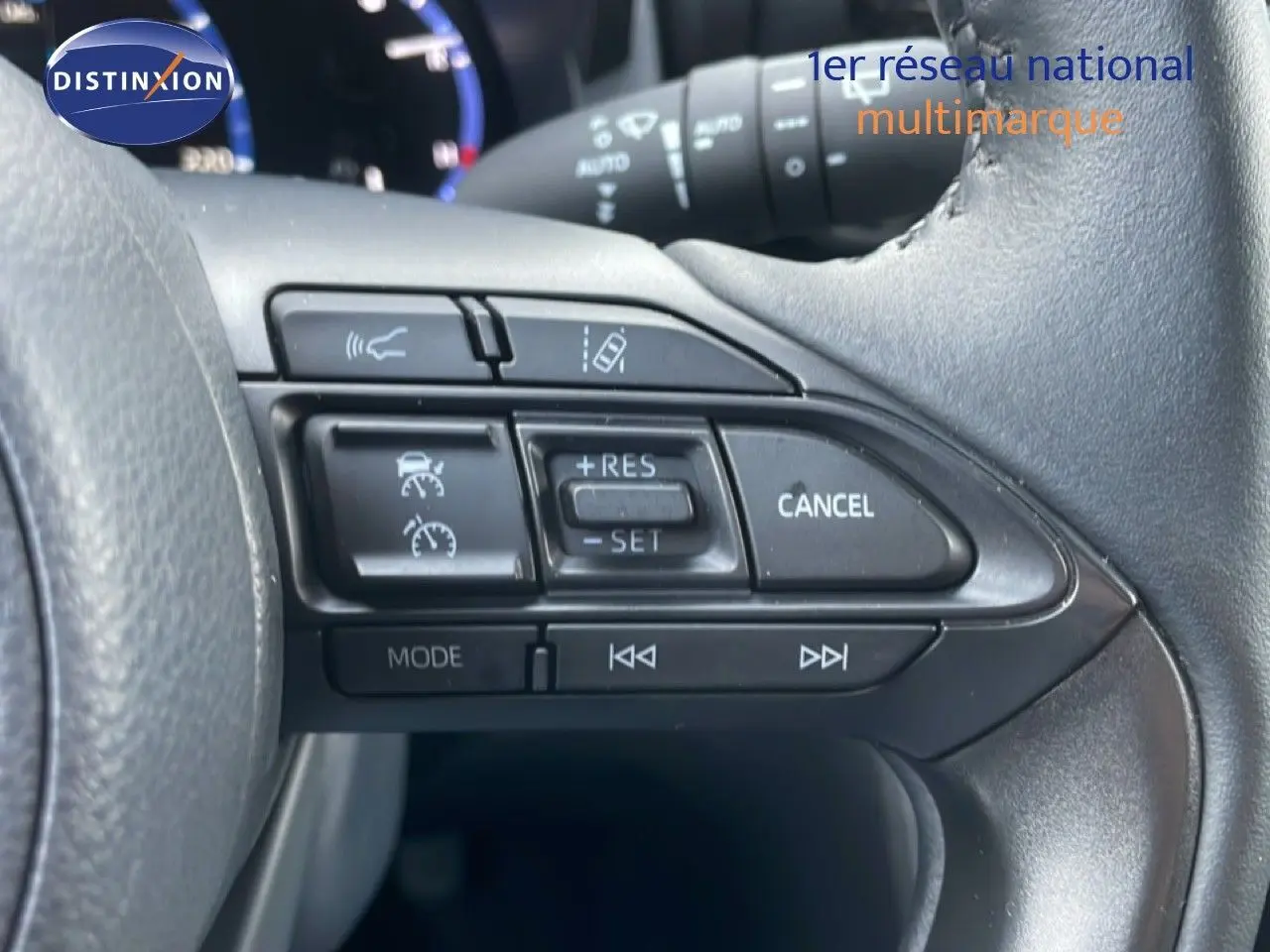 Gros plan sur les commandes au volant côté droit de la Toyota Yaris Cross Hybrid blanche, avec régulateur de vitesse et fonctions multimédia.