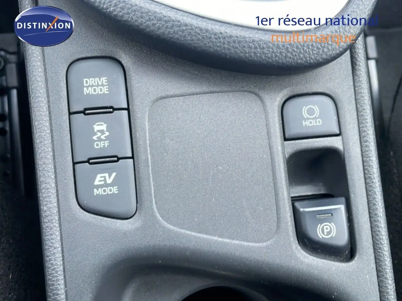 Gros plan sur la console centrale grise de la Toyota Yaris Cross Hybrid 2024, montrant les boutons Drive Mode, EV Mode et frein de stationnement.