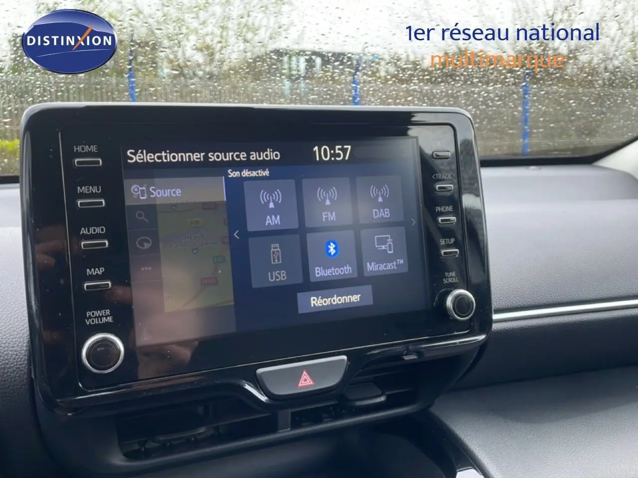 Vue intérieure centrée sur l'écran tactile multimédia de la Toyota Yaris Cross Hybrid blanche, avec commandes visibles.