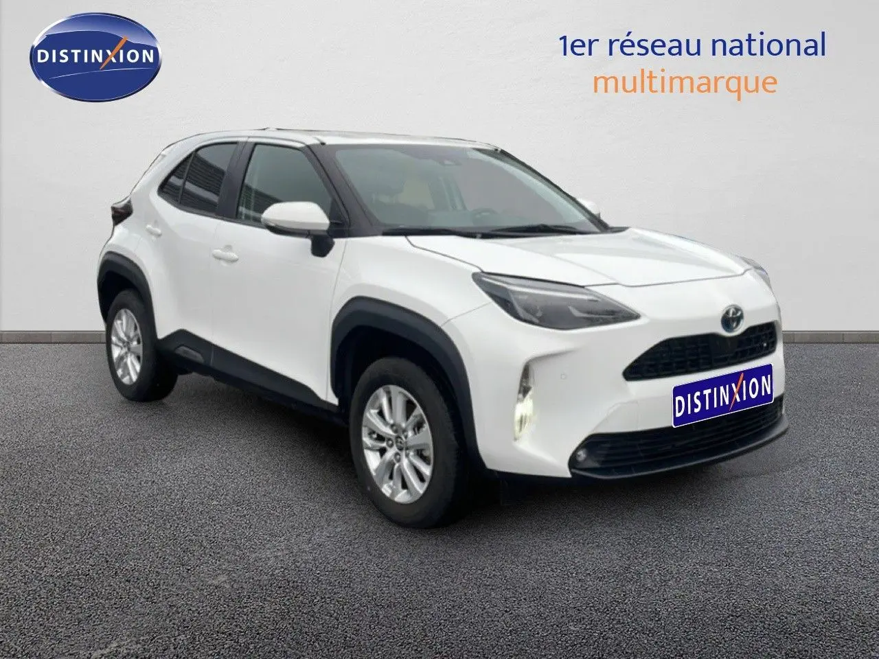 Toyota Yaris Cross blanc en 3/4 avant droit, avec calandre noire et protections d'ailes noires visibles.