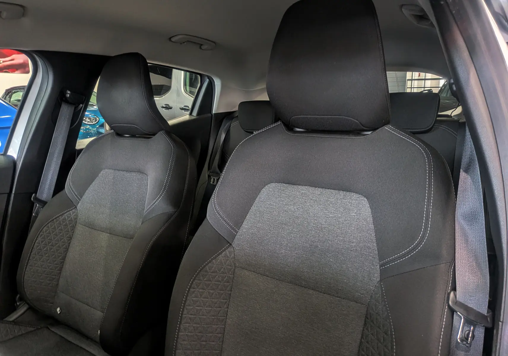 Vue intérieure rapprochée des sièges avant en tissu noir et gris de la Renault Clio V TCe 90 Gris Platine, version auto-école.