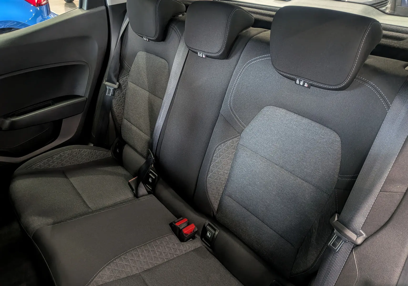 Vue intérieure des sièges arrière en tissu gris foncé de la Renault Clio V TCe 90 Auto-École, avec ceintures et appuie-têtes visibles.