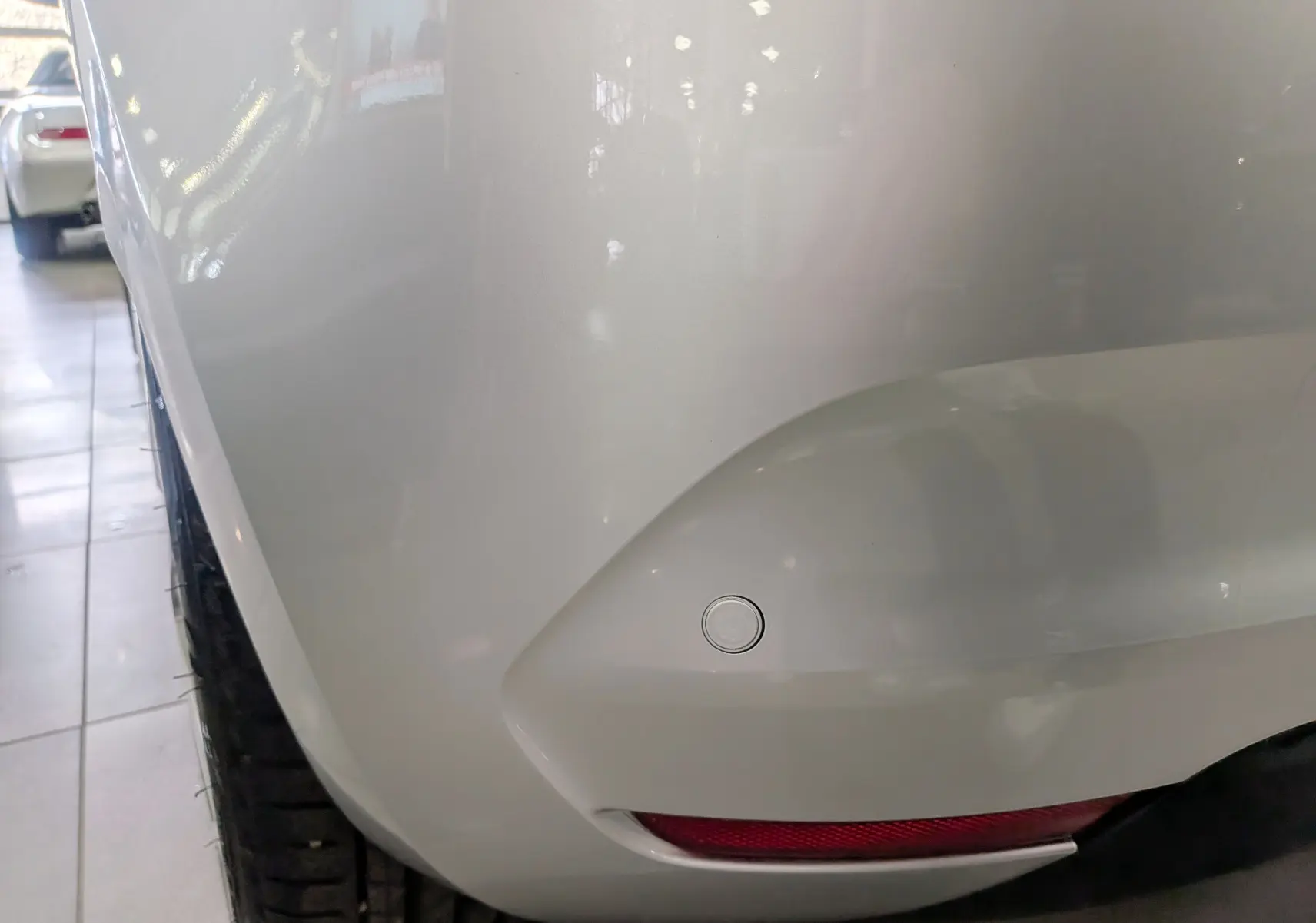 Gros plan sur l'angle arrière droit d'une Renault Clio V gris platine, mettant en valeur le capteur de recul et le feu arrière.