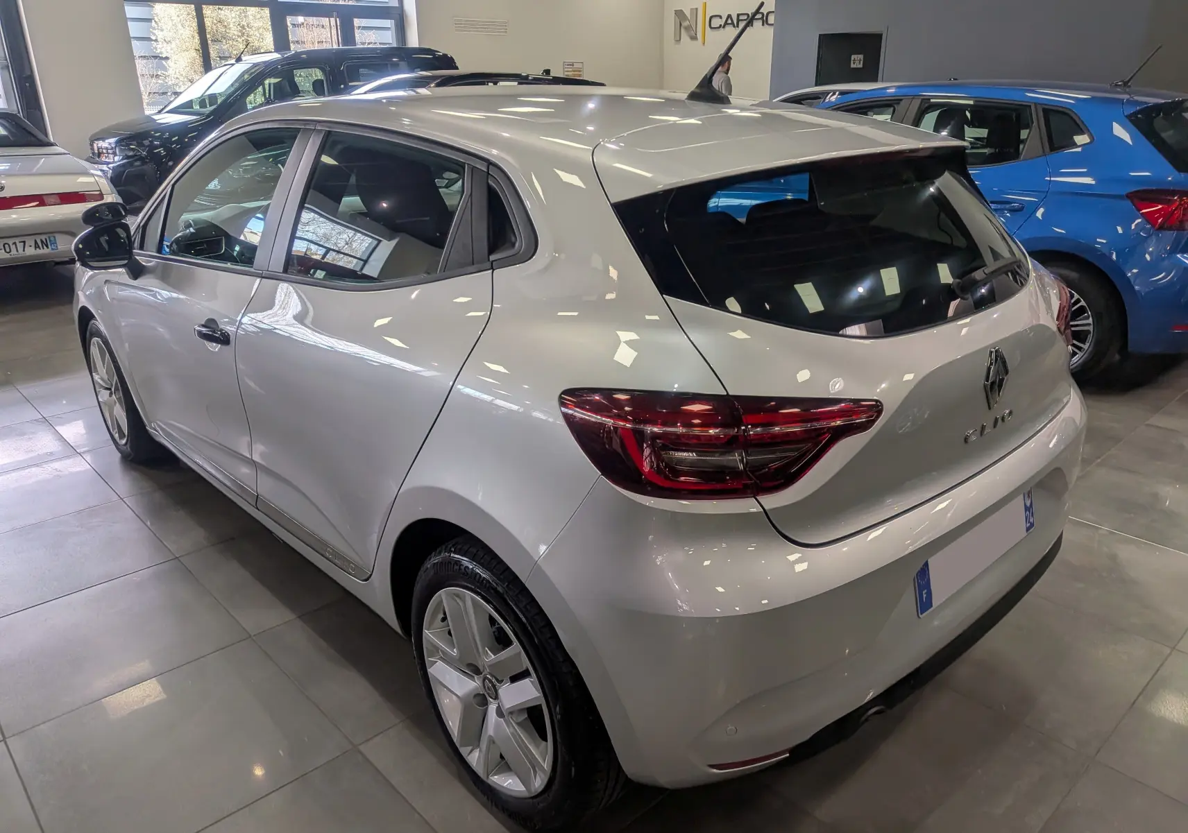 Vue 3/4 arrière droite d'une Renault Clio V gris platine en intérieur, avec feux arrière LED et jantes alliage.