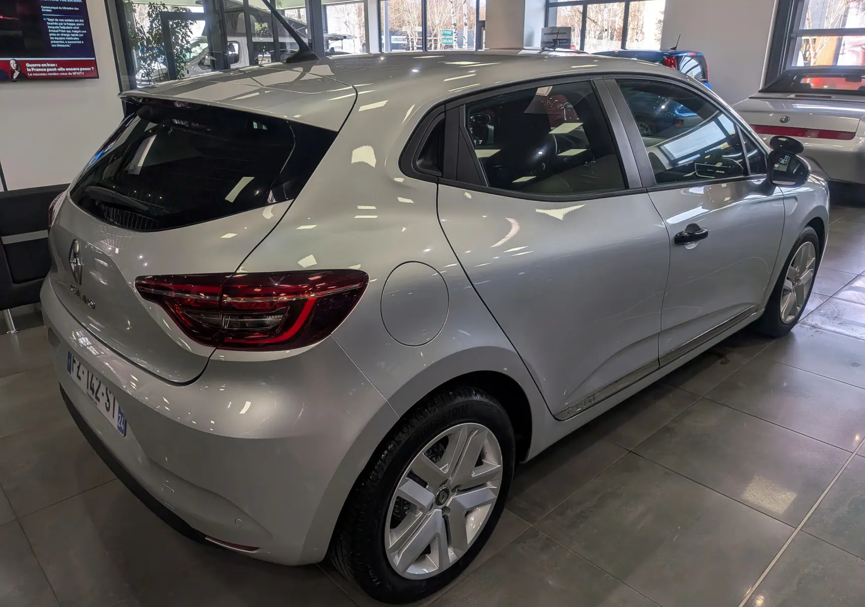 Vue 3/4 arrière droite d'une Renault Clio V gris platine en version auto-école, avec feux arrière LED et jantes alliage.