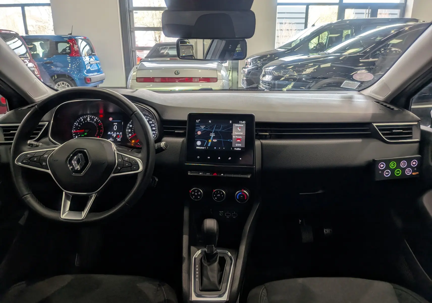 Vue intérieure avant de la Renault Clio V Gris Platine 2021, avec tableau de bord et écran tactile central visible.