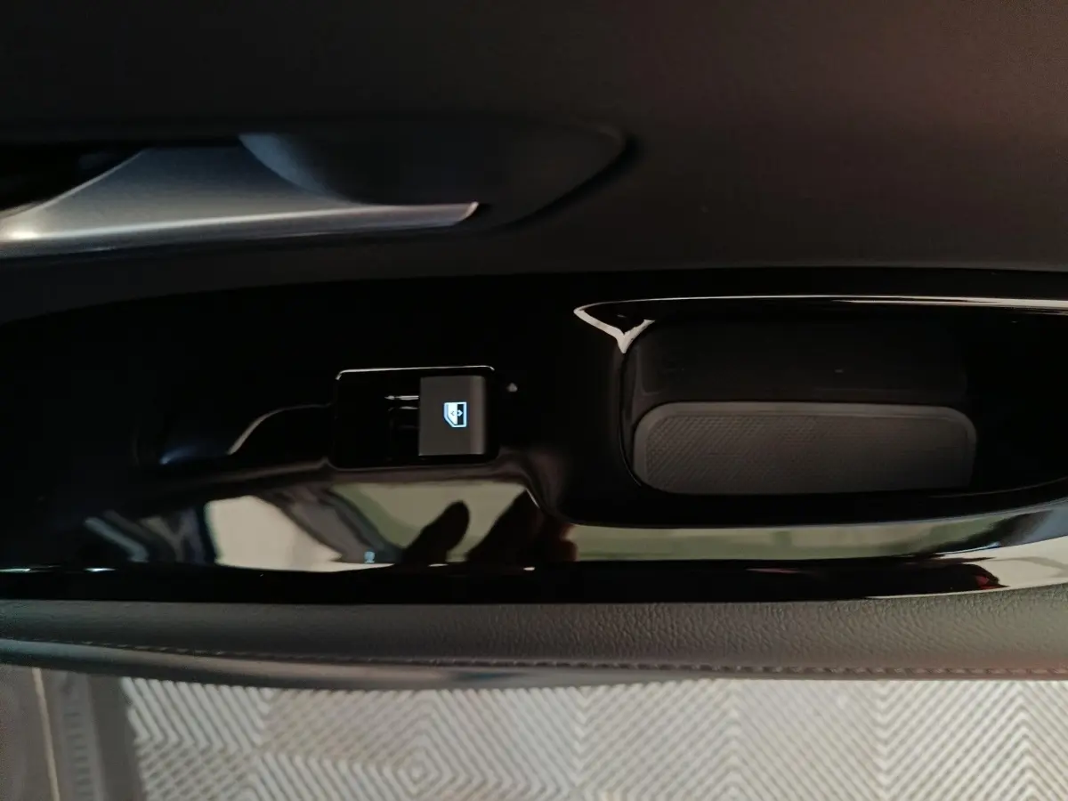 Gros plan sur le bouton de verrouillage des portes dans la portière intérieure noire d’un Hyundai Tucson gris foncé.