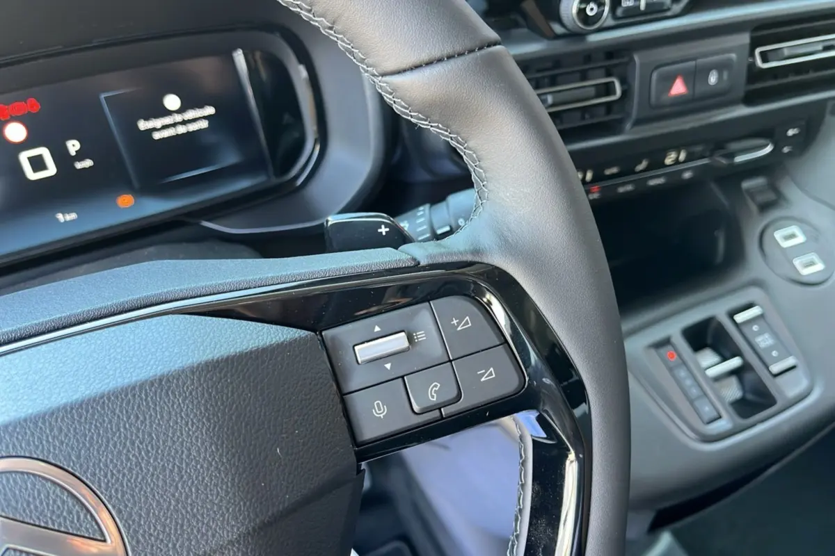 Gros plan sur le volant cuir multifonctions et tableau de bord numérique du Citroën Berlingo BlueHDi 130 2025.