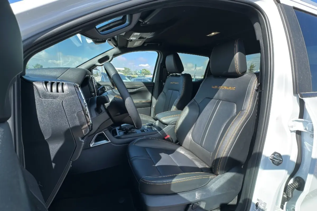Vue intérieure côté conducteur du Ford Ranger blanc 2026, sièges cuir noirs avec surpiqûres jaunes Wildtrak visibles.