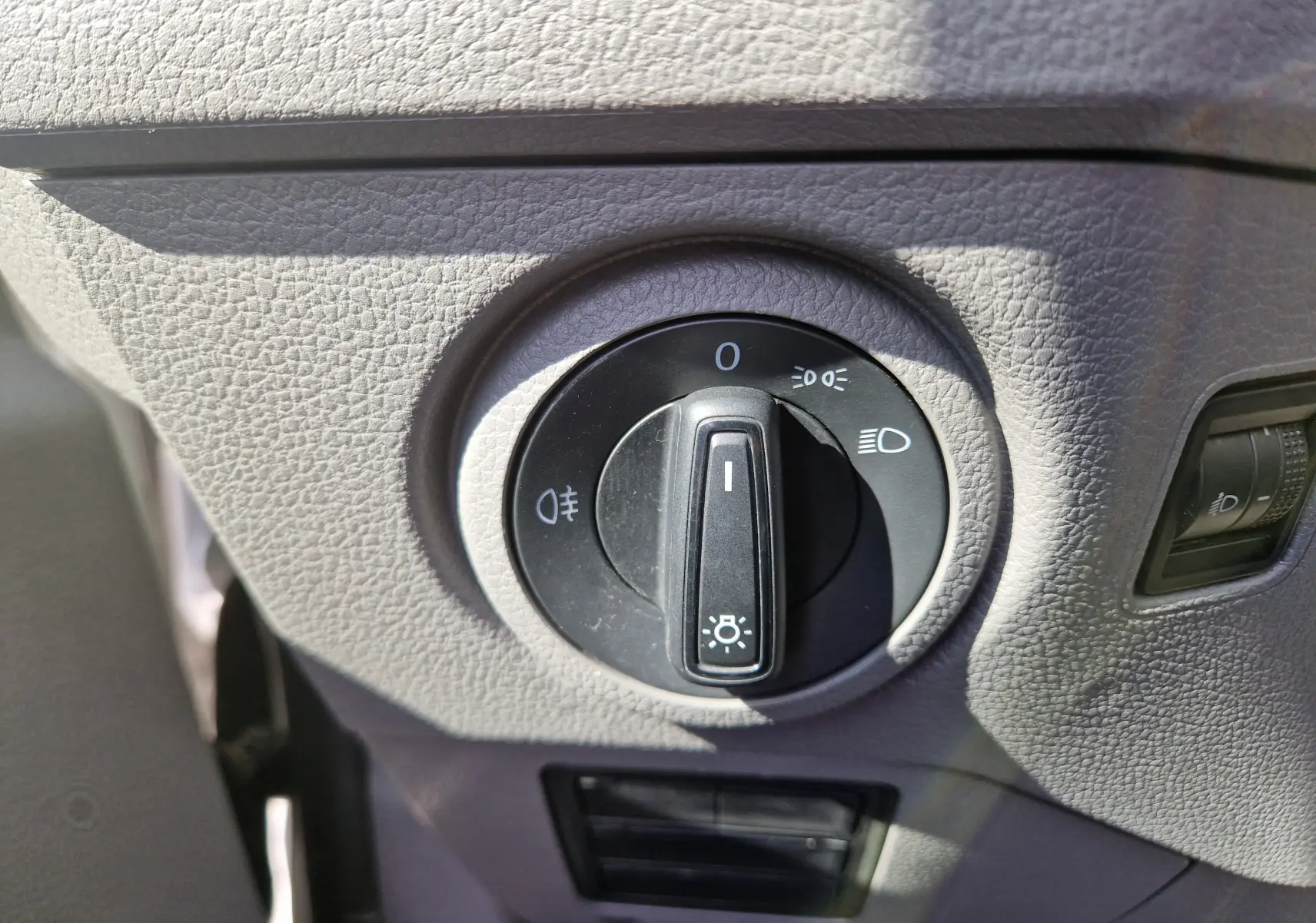 Gros plan sur le bouton de commande des phares dans l'habitacle gris du Volkswagen Crafter blanc de 2021.