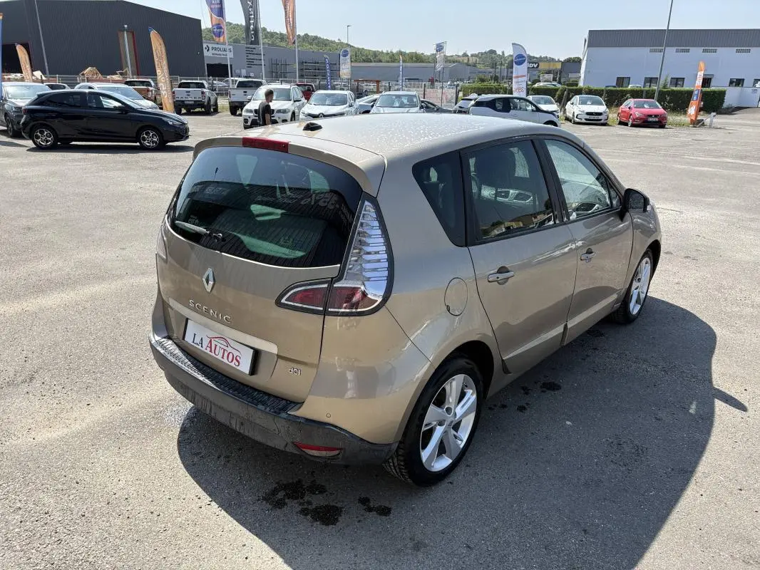 Renault Scénic III beige vue 3/4 arrière droit, vitres surteintées et jantes aluminium visibles en extérieur.
