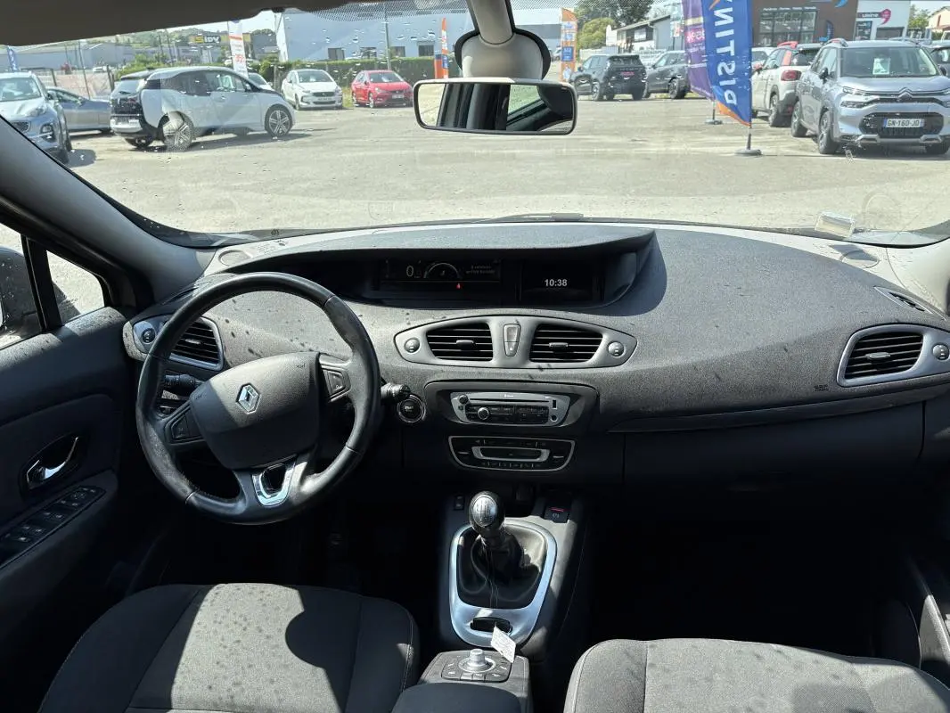 Vue intérieure avant du Renault Scénic beige 2015, volant cuir, tableau de bord avec écran multifonction et boîte manuelle.
