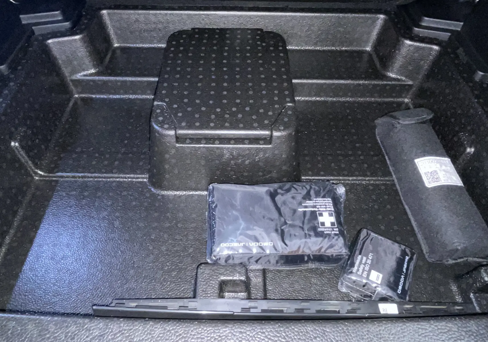Coffre ouvert du JAECOO J5 2026 en Phantom Grey Metal, vue plongeante sur rangement avec trousse de secours et accessoires.